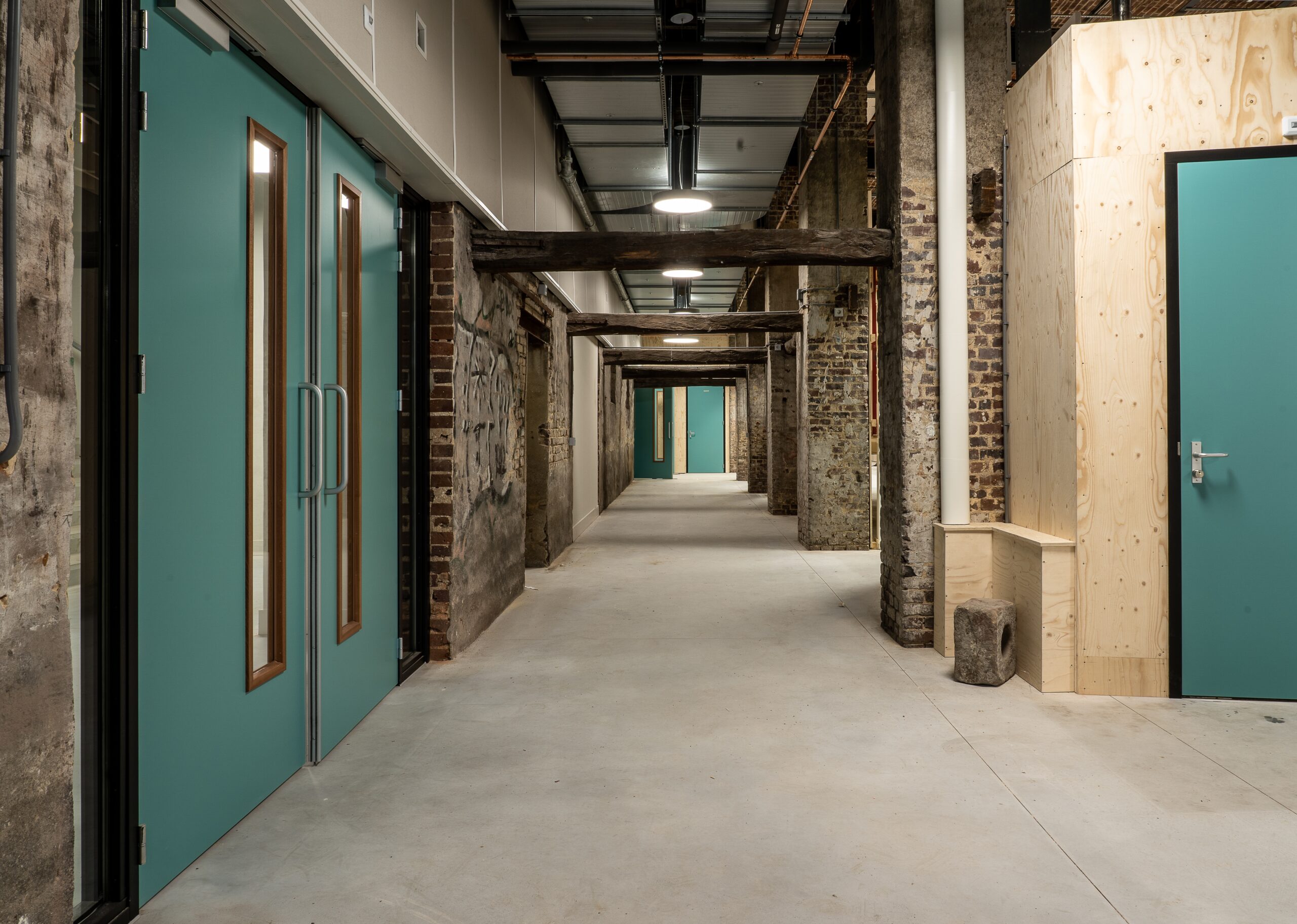 wide shot of a hallway with wide doors and brick columns in a building